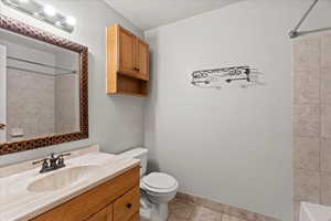 Full bathroom featuring vanity, toilet, tiled shower / bath combo, and tile patterned flooring