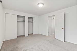 Unfurnished bedroom with two closets and light colored carpet