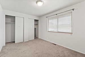 Unfurnished bedroom featuring light carpet and two closets