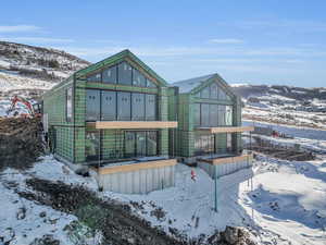 Snow covered rear of property with a mountain view