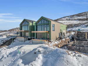 Snow covered rear of property with a mountain view