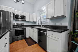 Kitchen featuring appliances with stainless steel finishes, light hardwood / wood-style floors, sink, and white cabinets