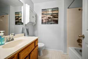 Full bathroom featuring hardwood / wood-style floors, vanity, toilet, and shower / tub combination