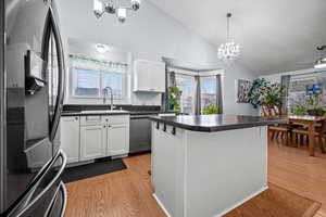 Kitchen featuring pendant lighting, sink, white cabinetry, black refrigerator with ice dispenser, and stainless steel dishwasher