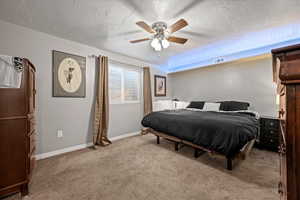 Carpeted bedroom featuring ceiling fan and a textured ceiling