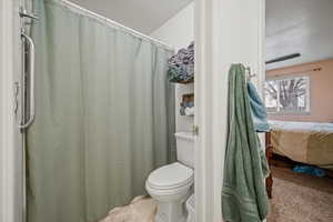 Bathroom with tile patterned flooring, a textured ceiling, and toilet