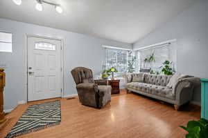 Living room with hardwood / wood-style flooring and vaulted ceiling