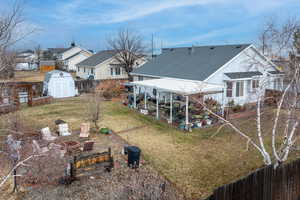 Rear view of property featuring a storage unit and a lawn