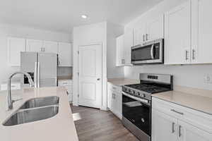 Kitchen featuring white cabinetry, sink, stainless steel appliances, and light wood-type flooring