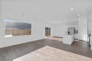 Kitchen with white cabinetry, an island with sink, appliances with stainless steel finishes, and hardwood / wood-style floors