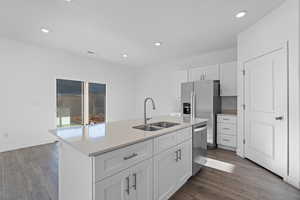 Kitchen with sink, dark wood-type flooring, white cabinetry, stainless steel appliances, and a center island with sink