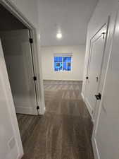 Hall with dark carpet and a textured ceiling