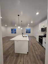 Kitchen featuring appliances with stainless steel finishes, sink, a kitchen island with sink, and white cabinets