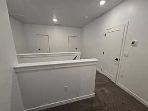 Hallway featuring dark colored carpet