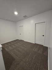 Empty room with a textured ceiling and dark colored carpet