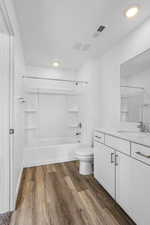 Full bathroom featuring vanity, tub / shower combination, hardwood / wood-style floors, and toilet