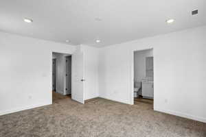 Unfurnished bedroom featuring ensuite bathroom and carpet floors