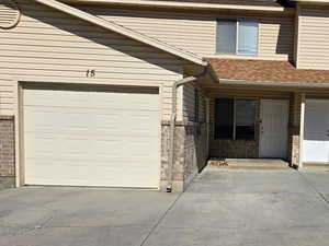 View of property featuring concrete driveway and brick siding