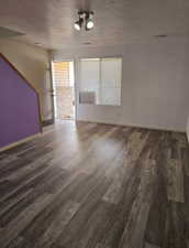 Unfurnished room with a textured ceiling and dark hardwood / wood-style flooring