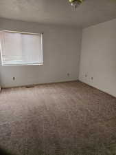 Carpeted empty room with a textured ceiling