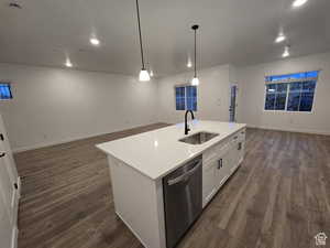 Kitchen featuring sink, white cabinetry, a center island with sink, decorative light fixtures, and stainless steel dishwasher