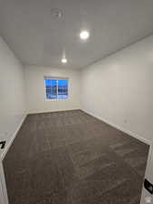 Spare room with a textured ceiling and dark carpet