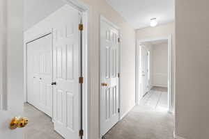 Hallway featuring light carpet and a textured ceiling