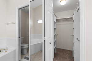 Bathroom featuring toilet and a tub to relax in