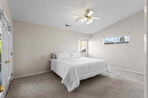 Bedroom featuring vaulted ceiling, ceiling fan, and carpet