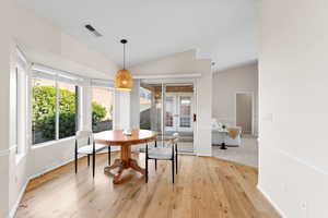 Dining room with a healthy amount of sunlight, lofted ceiling, and light wood-type flooring