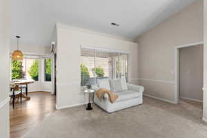 Sitting room featuring vaulted ceiling, light carpet, and a textured ceiling