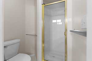 Bathroom featuring tile patterned floors, toilet, and a shower with door