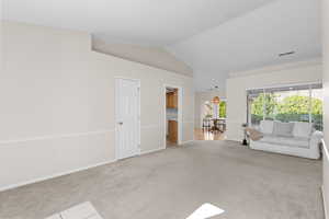 Unfurnished living room with lofted ceiling and light colored carpet