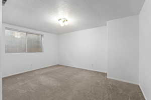 Carpeted empty room featuring a textured ceiling