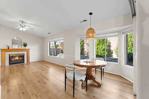 Dining area featuring ceiling fan, a fireplace, and light hardwood / wood-style flooring