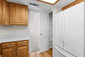 Kitchen with light wood-type flooring, a textured ceiling, and white fridge