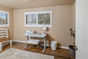 Home office with dark wood-type flooring and a textured ceiling