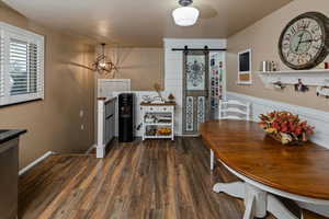 Dining space featuring a barn door, a notable chandelier, and dark hardwood / wood-style flooring