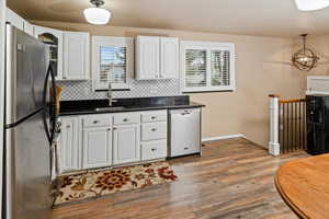 Kitchen with sink, white cabinets, backsplash, hanging light fixtures, and stainless steel appliances