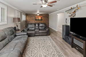 Living room with ornamental molding, ceiling fan, and light hardwood / wood-style flooring