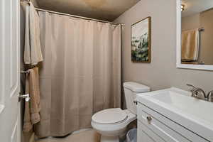 Bathroom with vanity, a textured ceiling, and toilet