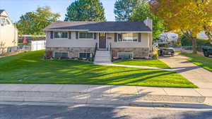 Bi-level home featuring a front yard and cooling unit