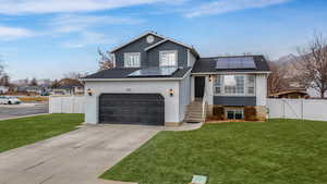 View of front of house featuring a front lawn and solar panels