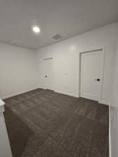 Unfurnished room featuring dark colored carpet