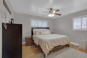 Primary Bedroom with ceiling fan and hardwood flooring