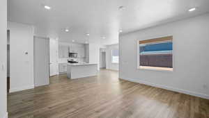 Unfurnished living room with sink, light hardwood / wood-style floors, and a textured ceiling