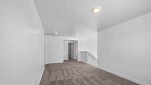 Empty room with carpet floors and a textured ceiling