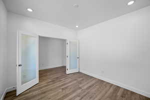 Unfurnished bedroom with french doors and light hardwood / wood-style floors