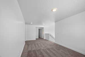 Carpeted spare room featuring a textured ceiling