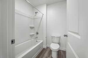 Bathroom featuring hardwood / wood-style flooring, shower / tub combination, and toilet